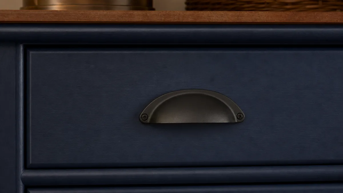 a close-up of a dresser drawer front with matte black arched hardware…
