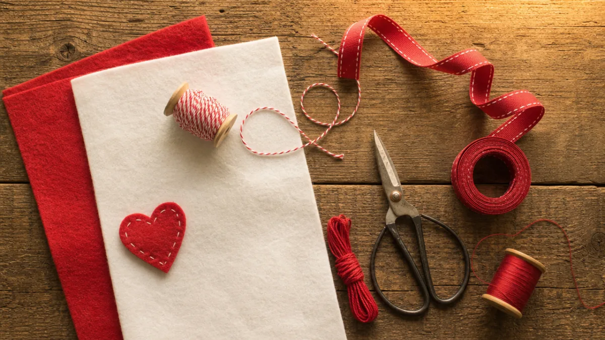 a flat lay of red and white felt sheets, scissors, ribbon, and…
