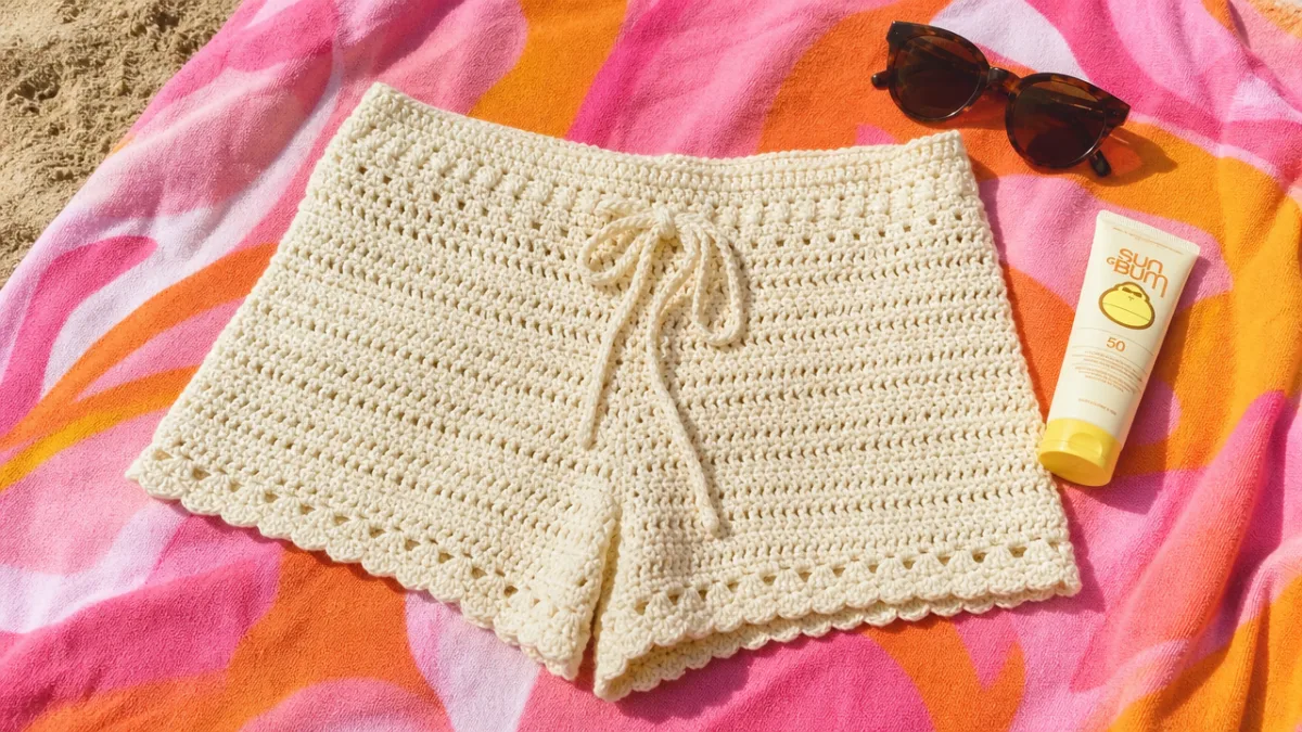 a pair of handmade cream cotton crochet shorts laid flat on a…