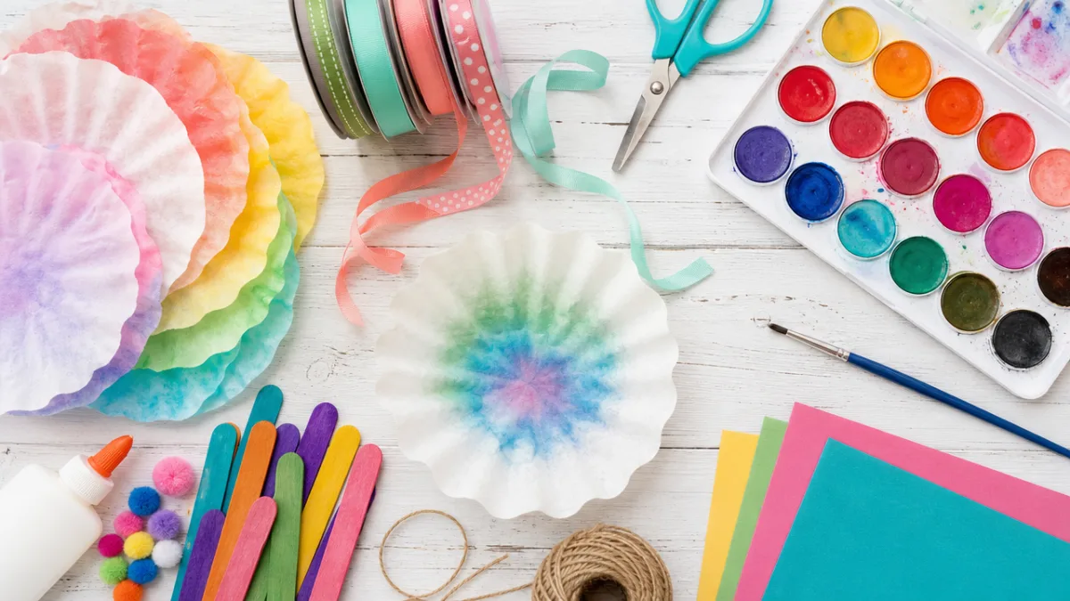 a flat lay of colorful craft supplies including coffee filters, ribbon, and…