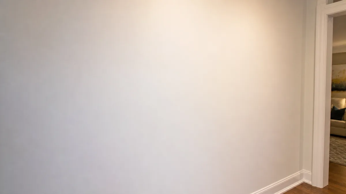 freshly painted white wall with a perfectly smooth repaired patch, warm residential…