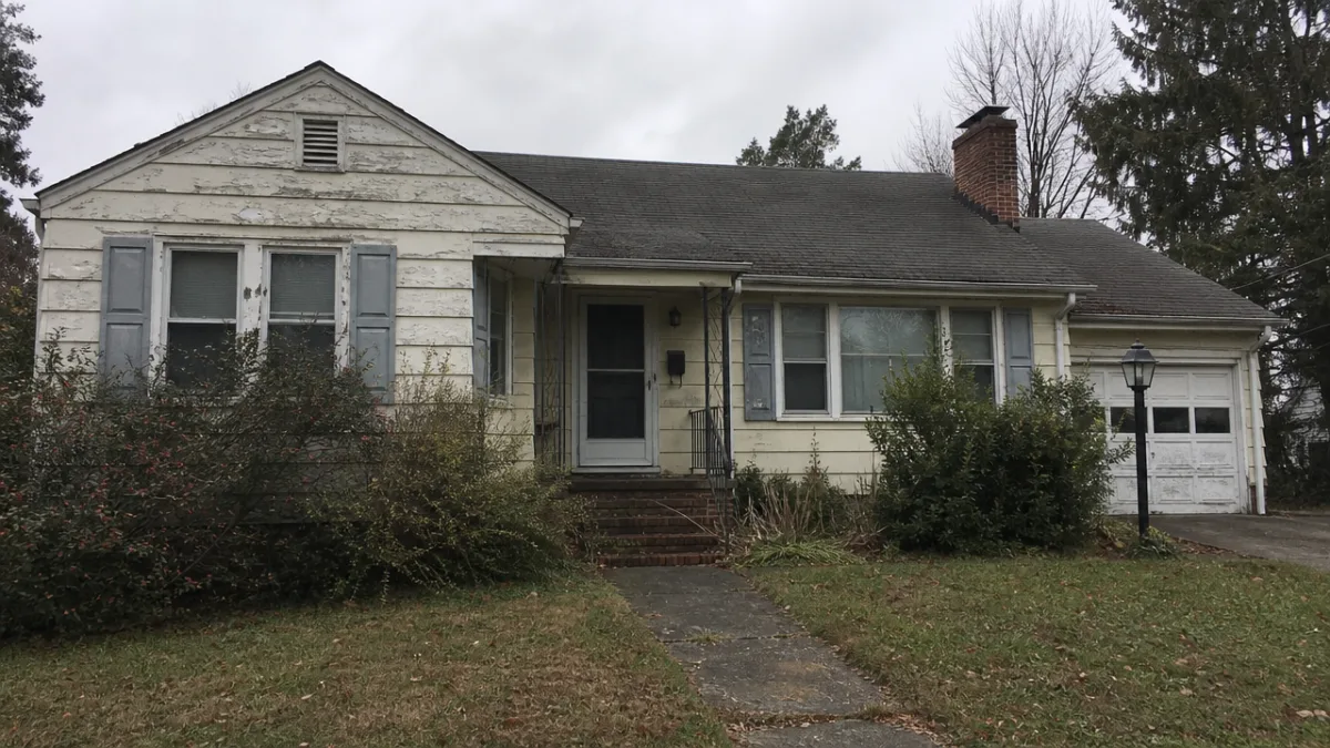 a weathered suburban home exterior before renovation, overcast natural light emphasizing faded…