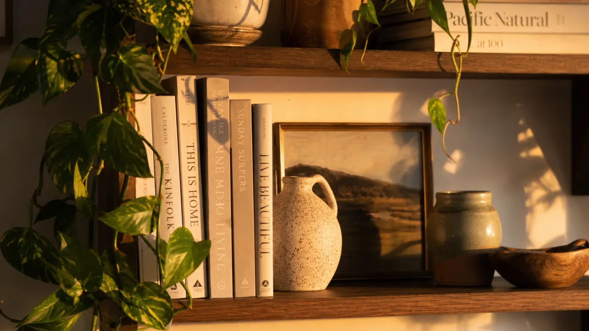a close-up of a beautifully styled shelf with ceramics, trailing plants, and…