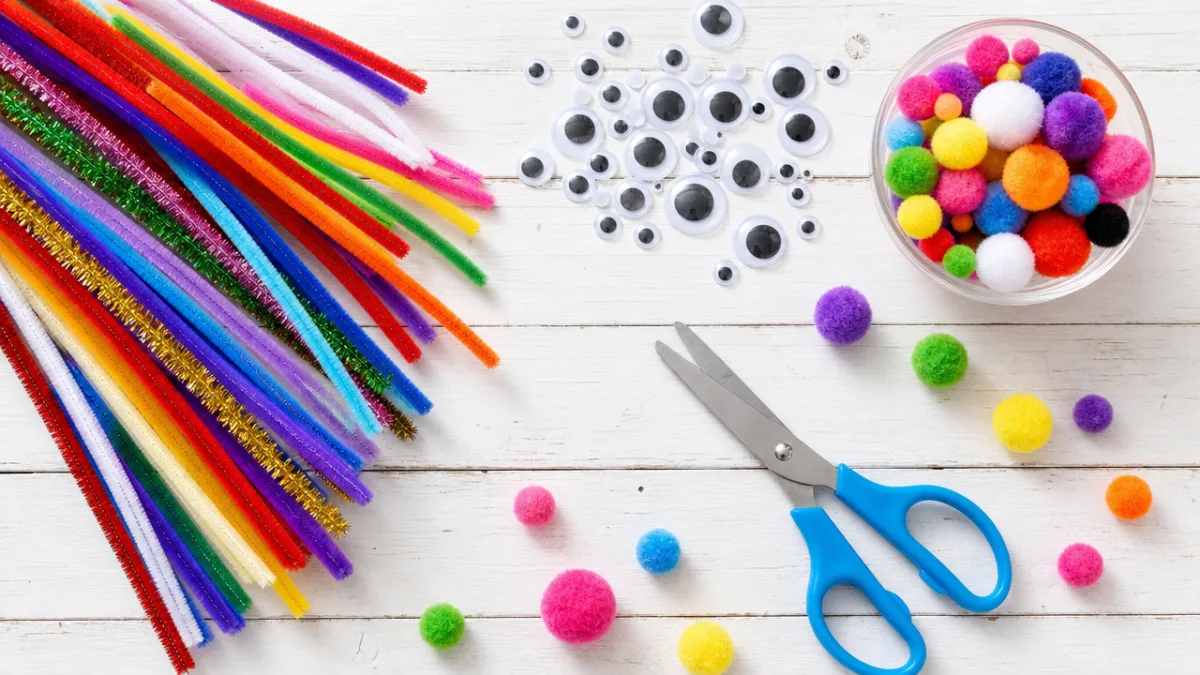 a flat lay of colorful pipe cleaners, googly eyes, pom-poms and craft…