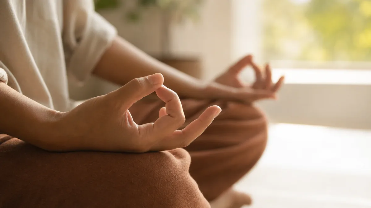 a close-up of hands in Gyan mudra resting on crossed knees, soft…