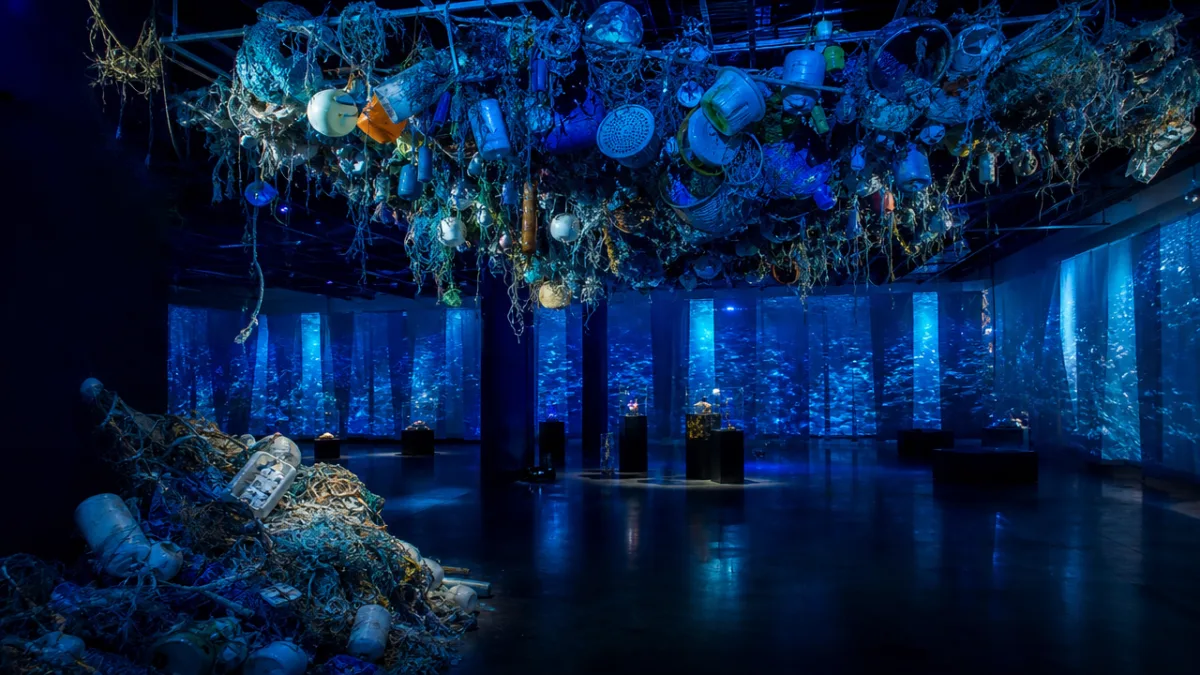 an immersive environmental art installation with ocean debris, blue dramatic lighting and…