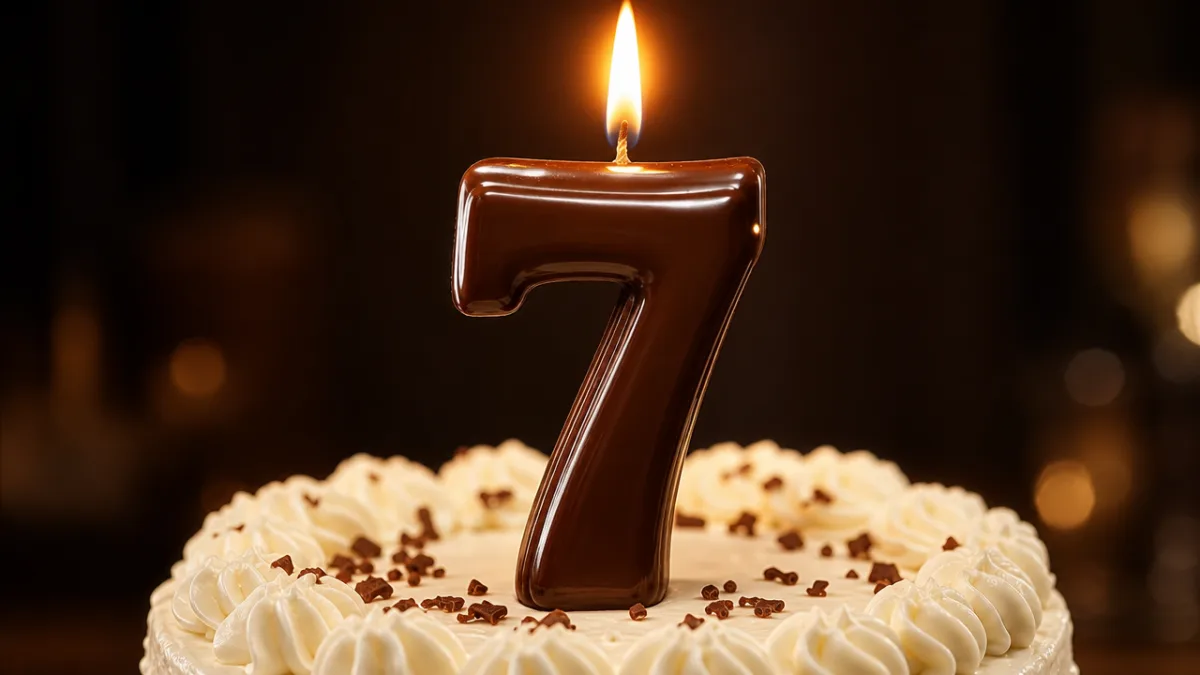 a close-up of a glossy chocolate number candle on a white frosted…