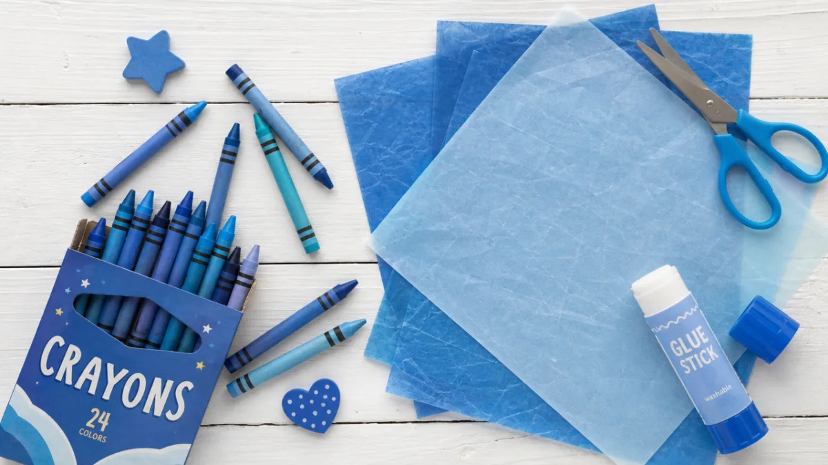 a flat lay of colorful blue crayons, wax paper, and crafting tools…