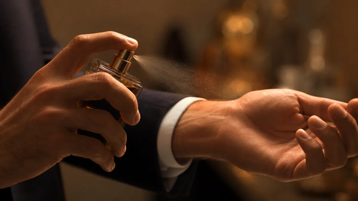 a close-up of a man's wrist being sprayed with cologne, warm studio…