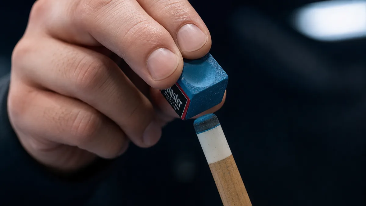 a focused close-up of a player's hand chalking a pool cue tip…