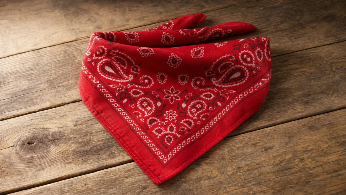 a finished folded bandana in red paisley fabric displayed on a rustic…