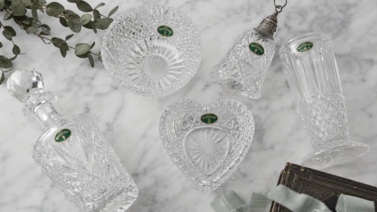 a styled flat lay of antique Waterford crystal pieces on a white…