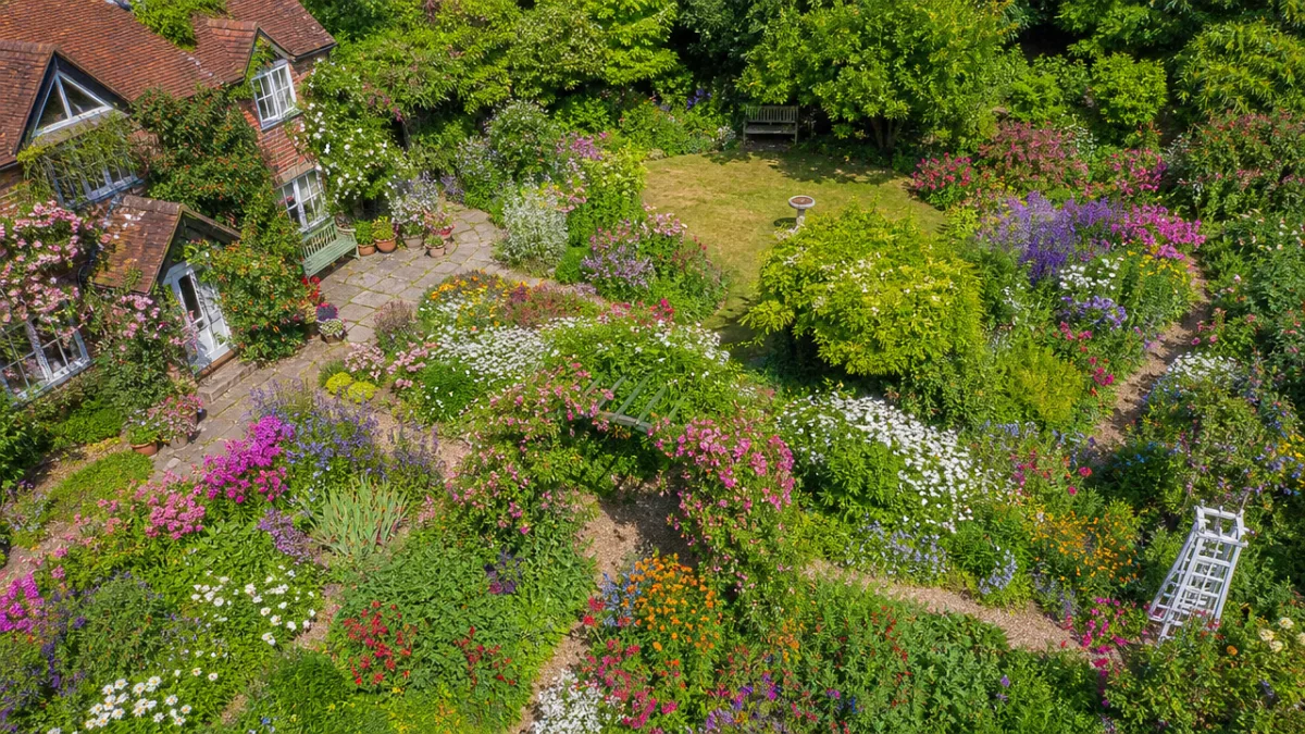 an aerial drone view of a fully bloomed cottage garden at peak…