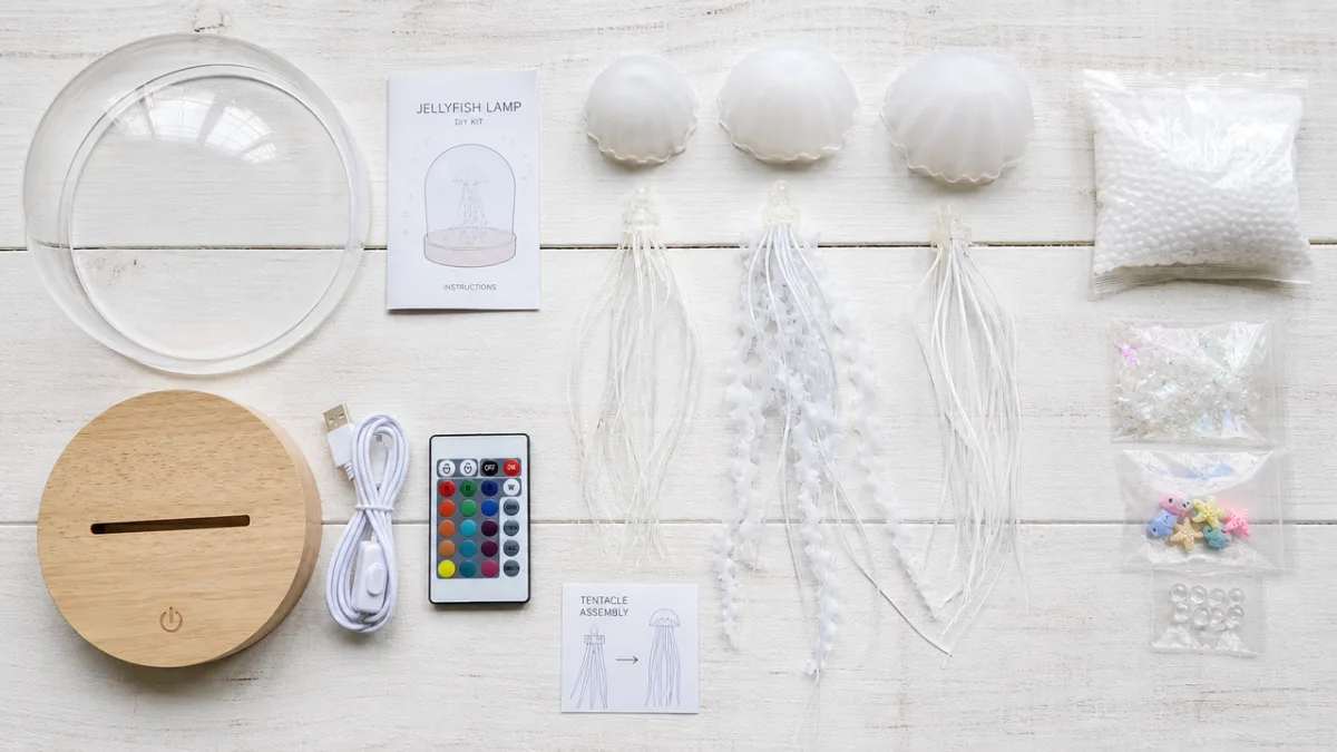 a flat lay of jellyfish lamp crafting materials on a white wooden…