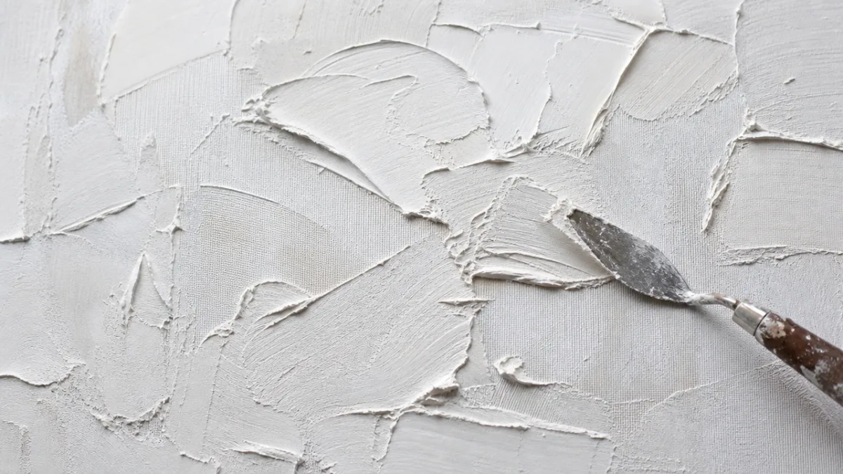 close-up of a large textured canvas mid-creation showing palette knife strokes in…