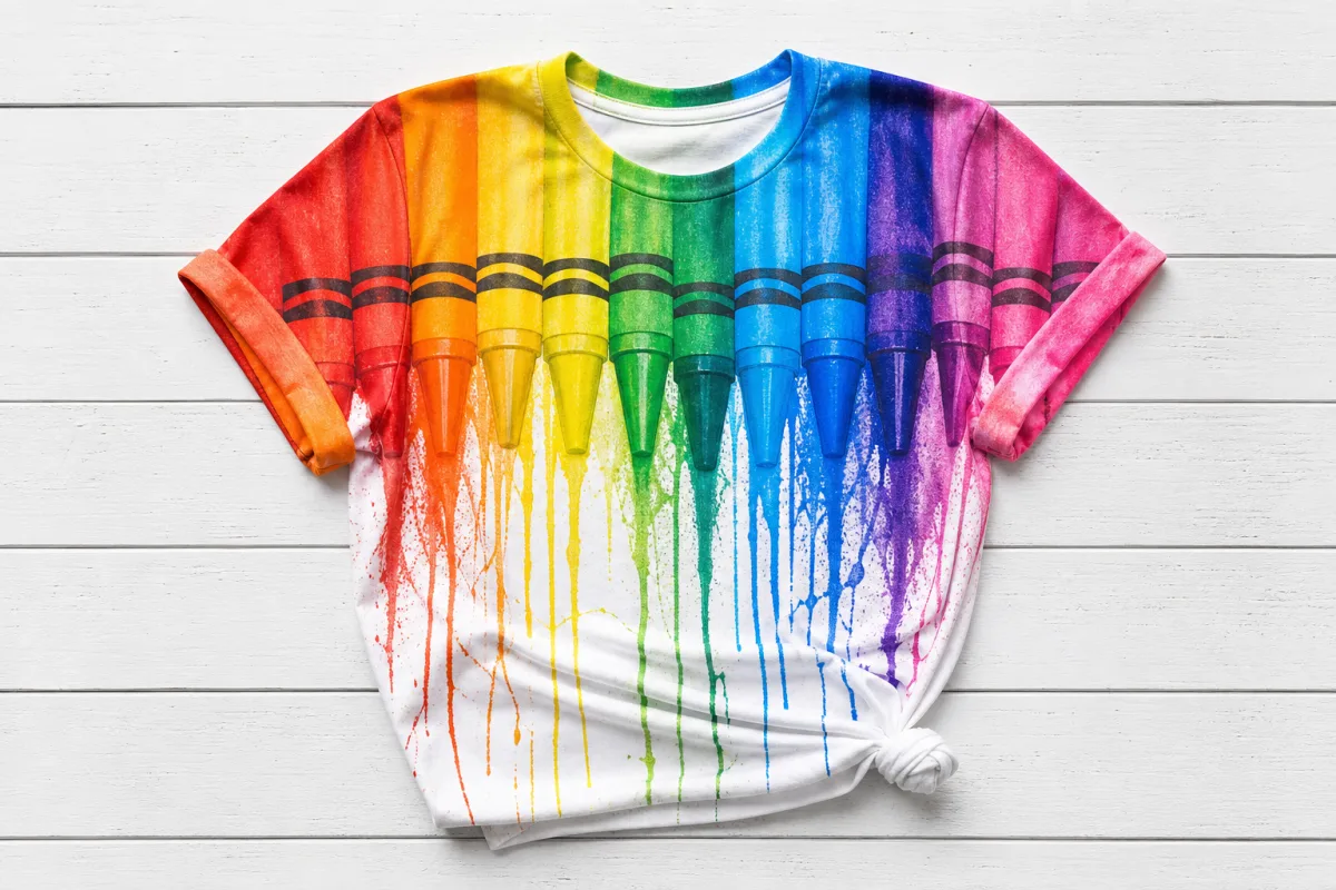 a flat lay of a vibrant multicolor rainbow crayon art t-shirt on…